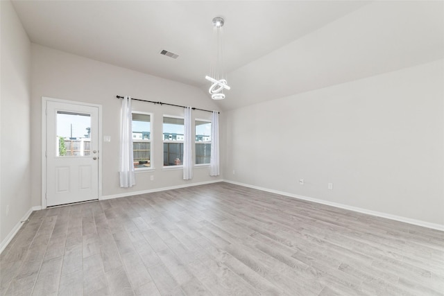 empty room featuring light hardwood / wood-style floors and vaulted ceiling