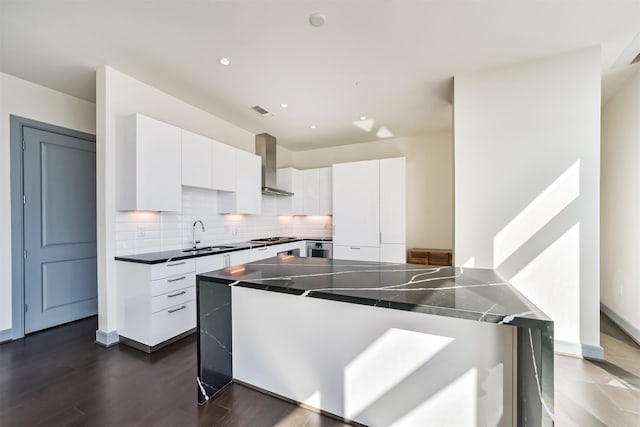 kitchen featuring sink, wall chimney exhaust hood, dark hardwood / wood-style flooring, decorative backsplash, and white cabinets