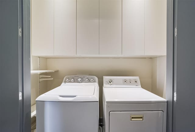 washroom with washer and dryer and cabinets