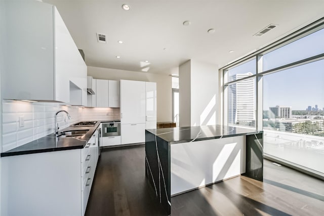 kitchen featuring white cabinets, backsplash, dark hardwood / wood-style floors, and stainless steel oven