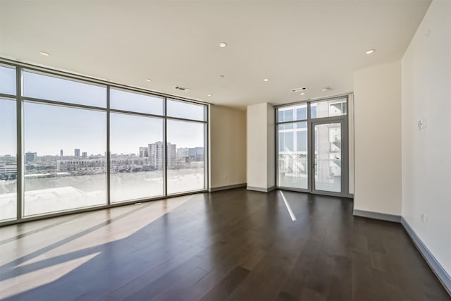 spare room with dark hardwood / wood-style flooring, plenty of natural light, and a wall of windows