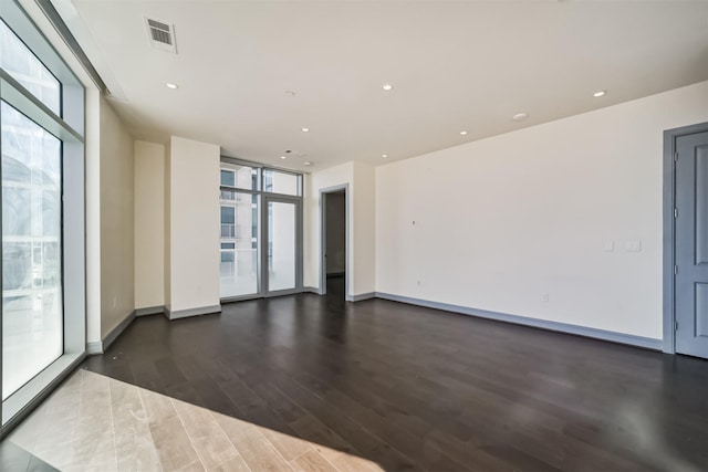 empty room featuring floor to ceiling windows and dark hardwood / wood-style flooring