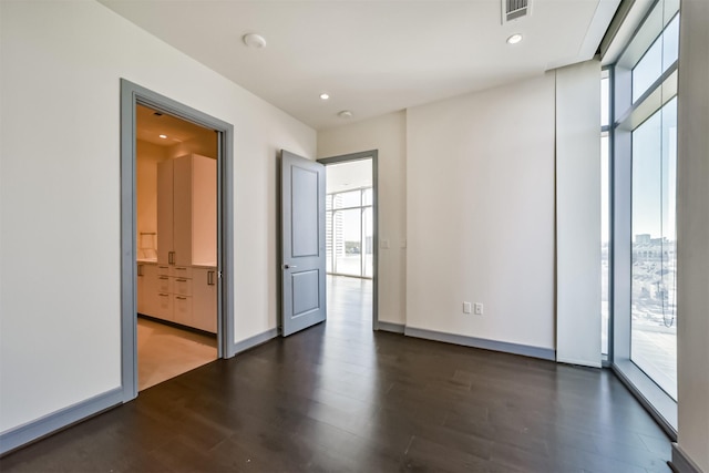 unfurnished room featuring plenty of natural light, floor to ceiling windows, and dark hardwood / wood-style flooring