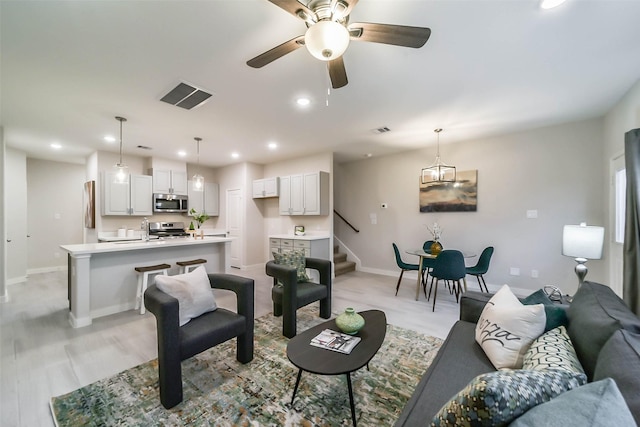 living room featuring ceiling fan, sink, and light hardwood / wood-style flooring