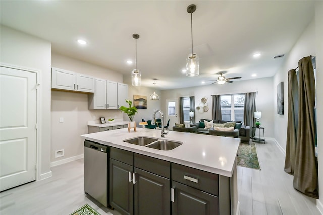 kitchen with light wood-type flooring, stainless steel dishwasher, ceiling fan, sink, and white cabinetry