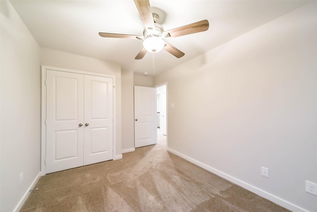 unfurnished bedroom featuring a closet, light colored carpet, and ceiling fan