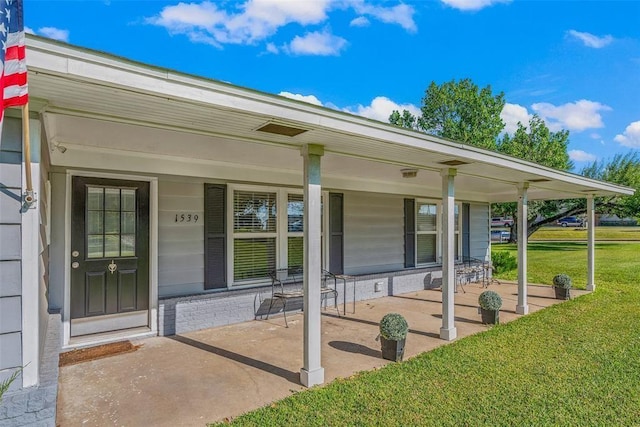 view of exterior entry with a porch and a yard