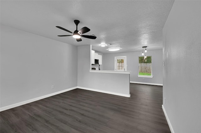 unfurnished living room with a textured ceiling, dark hardwood / wood-style flooring, and ceiling fan