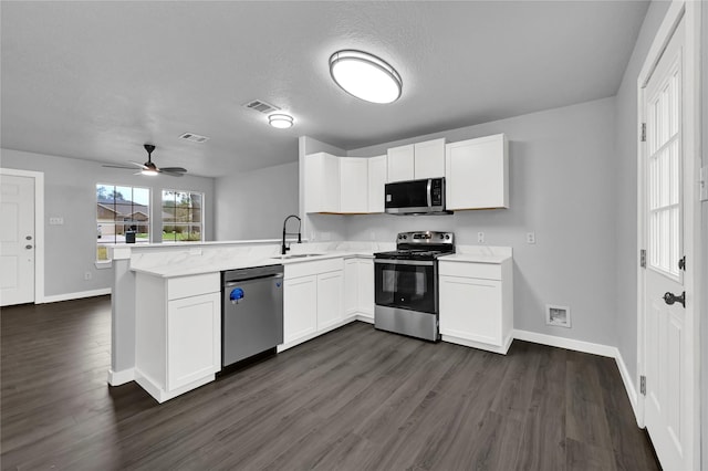 kitchen with kitchen peninsula, dark hardwood / wood-style flooring, stainless steel appliances, sink, and white cabinets