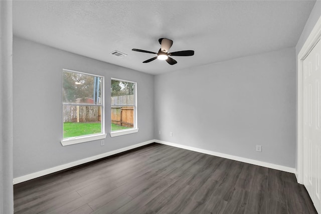 unfurnished room featuring a textured ceiling, ceiling fan, and dark hardwood / wood-style floors