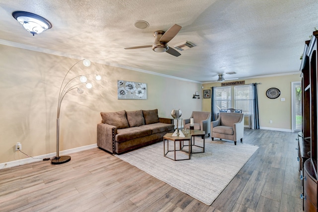 living room with ceiling fan, light hardwood / wood-style floors, a textured ceiling, and ornamental molding