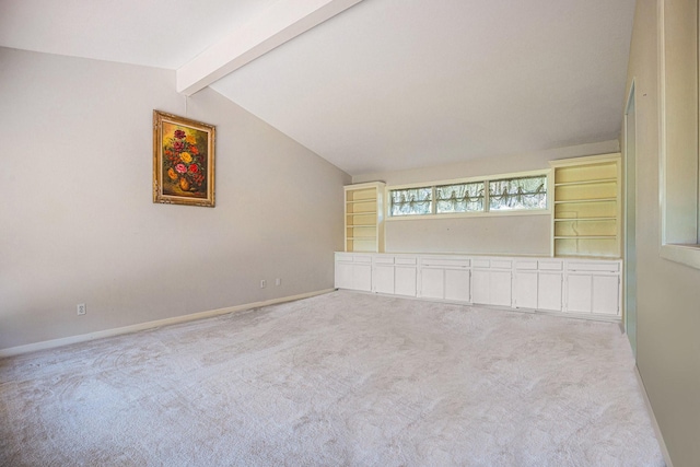 empty room with vaulted ceiling with beams, built in features, and light colored carpet