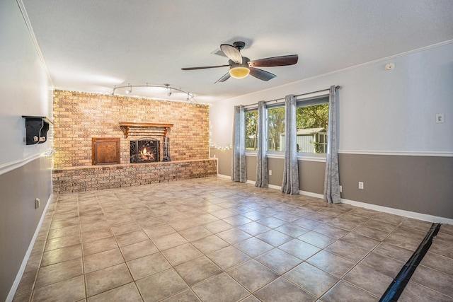 unfurnished living room with ceiling fan, a fireplace, brick wall, and ornamental molding