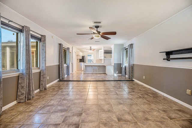 unfurnished living room with ceiling fan, crown molding, and tile patterned flooring