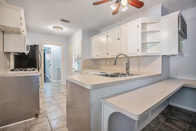 kitchen featuring white cabinets, oven, kitchen peninsula, and sink