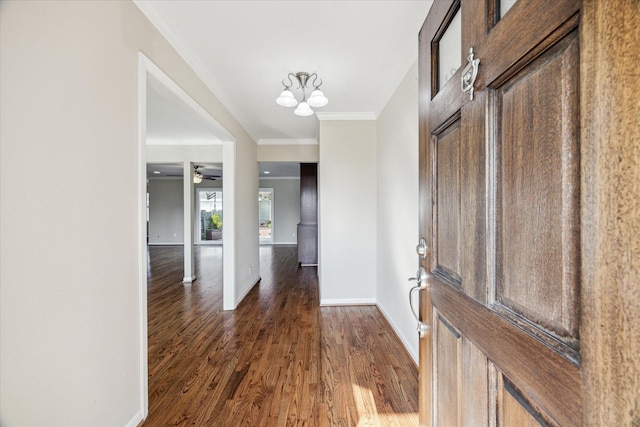 entryway featuring crown molding, dark wood-type flooring, and a notable chandelier