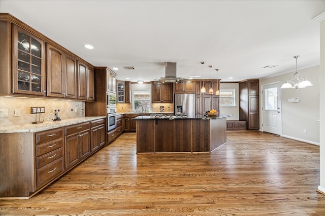 kitchen with decorative light fixtures, island range hood, a kitchen island, and appliances with stainless steel finishes