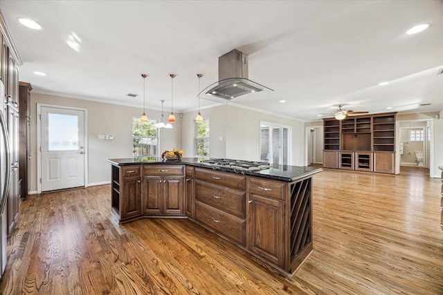 kitchen featuring island range hood, a center island, decorative light fixtures, and ornamental molding