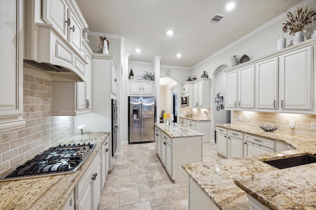 kitchen featuring light stone countertops, a center island, stainless steel appliances, and white cabinetry