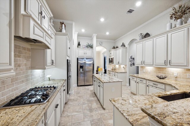 6615 Cottonwood Crest Ln, Katy, TX 77493 - kitchen with stainless steel appliances, arched walkways, decorative backsplash, light stone countertops, and crown molding