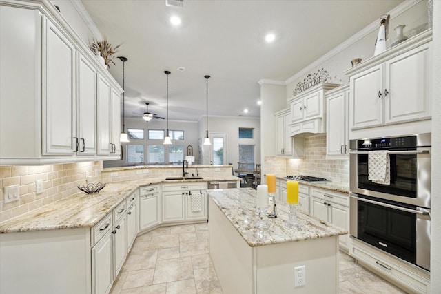 kitchen featuring kitchen peninsula, appliances with stainless steel finishes, crown molding, a center island, and hanging light fixtures