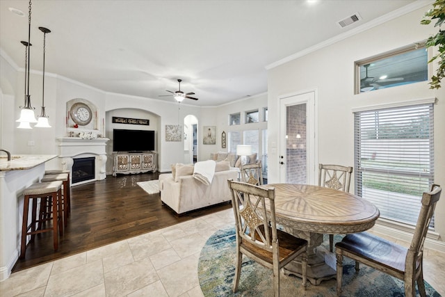 6615 Cottonwood Crest Ln, Katy, TX 77493 - tiled dining room featuring a ceiling fan, ornamental molding, healthy amount of natural light, a fireplace, and arched walkways