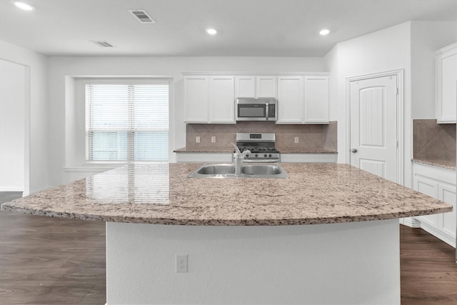 kitchen with a center island with sink, dark hardwood / wood-style floors, tasteful backsplash, white cabinetry, and stainless steel appliances