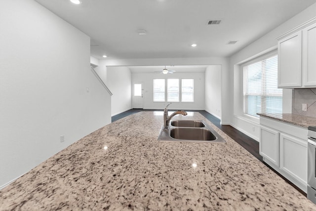 kitchen with light stone countertops, white cabinetry, a healthy amount of sunlight, and sink