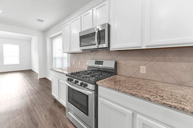 kitchen with stainless steel appliances, light stone counters, dark hardwood / wood-style flooring, decorative backsplash, and white cabinets