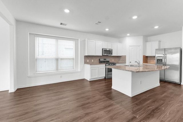 kitchen with dark wood-type flooring, sink, an island with sink, appliances with stainless steel finishes, and white cabinetry