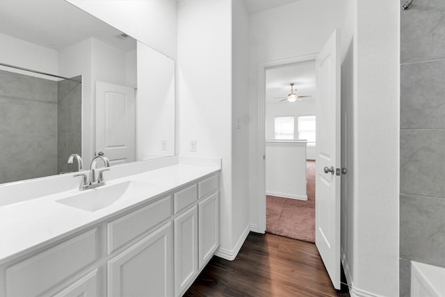 bathroom with hardwood / wood-style floors, ceiling fan, tiled shower, and vanity