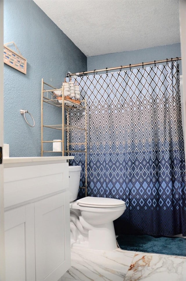 bathroom with vanity, toilet, and a textured ceiling