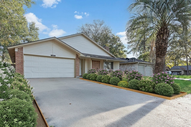 ranch-style house featuring an attached garage, driveway, a chimney, and brick siding