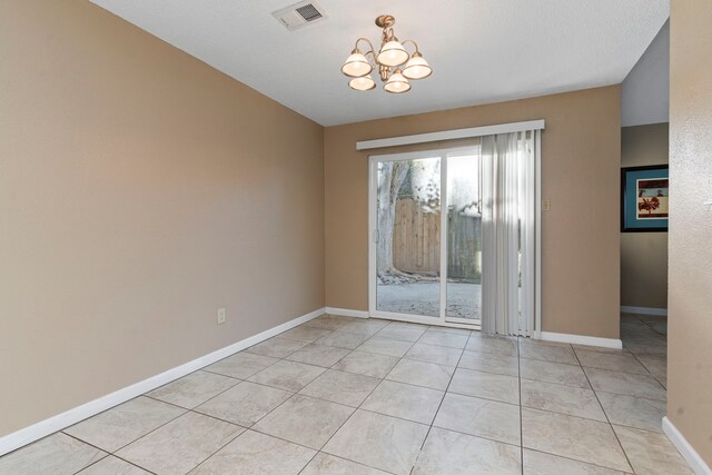 spare room featuring light tile patterned floors, a textured ceiling, and an inviting chandelier