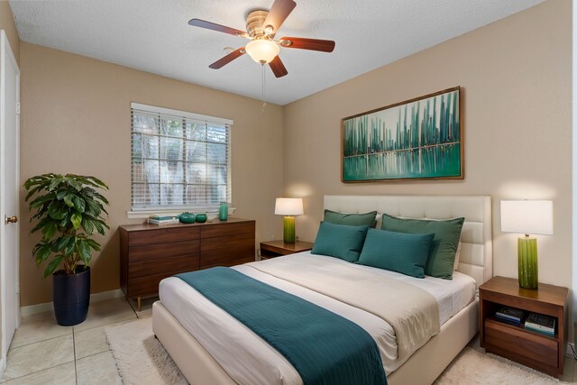 bedroom featuring ceiling fan, light tile patterned flooring, and a textured ceiling