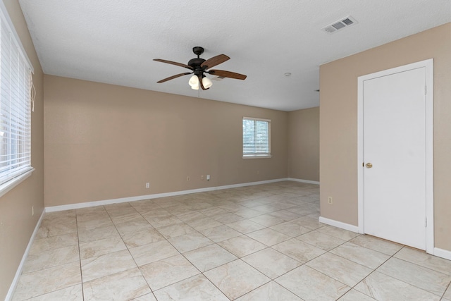 spare room with light tile patterned floors, a textured ceiling, and ceiling fan