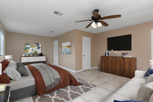 bedroom featuring ceiling fan, light tile patterned floors, and a textured ceiling