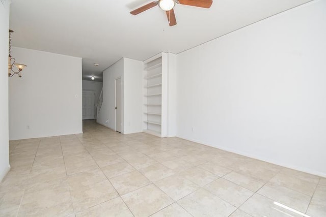 empty room with light tile patterned floors and ceiling fan with notable chandelier