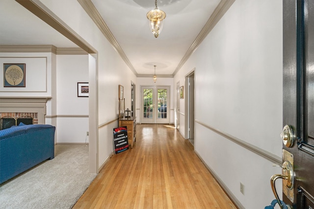 hall with french doors, light wood-type flooring, and crown molding