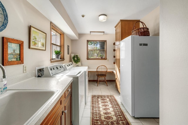 laundry room featuring light tile patterned floors, washing machine and dryer, and sink