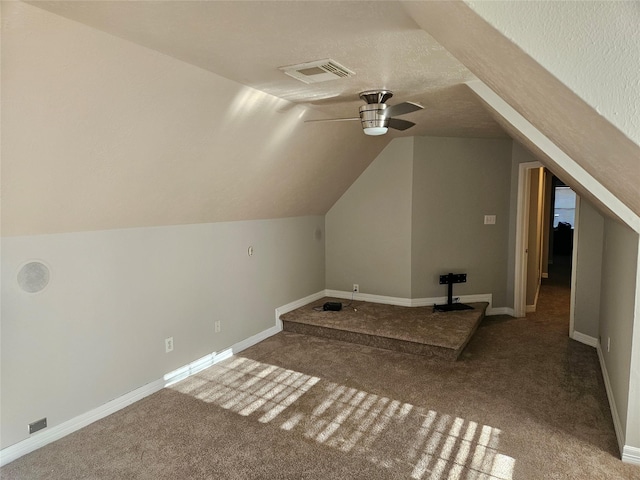 additional living space with vaulted ceiling, carpet flooring, a textured ceiling, and ceiling fan