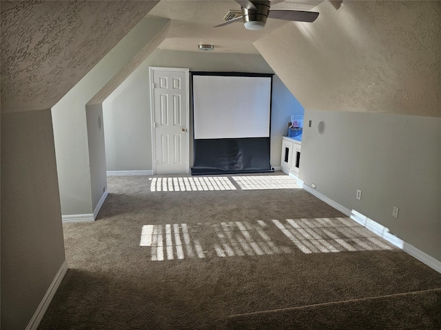 additional living space with ceiling fan, lofted ceiling, carpet flooring, and a textured ceiling