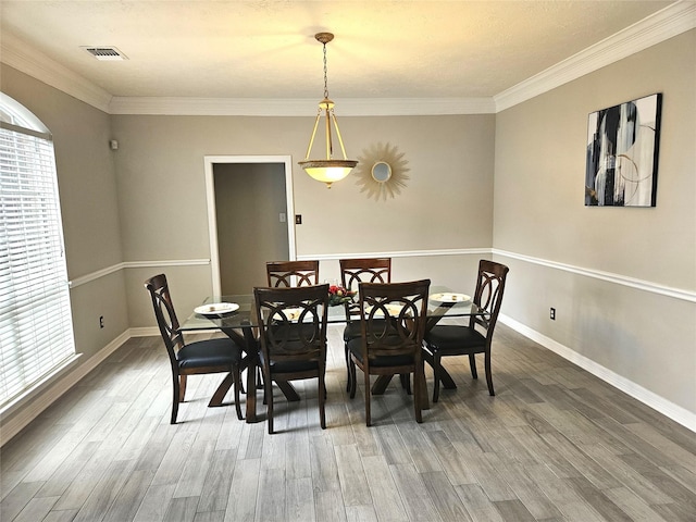 dining space with hardwood / wood-style floors, a wealth of natural light, and ornamental molding