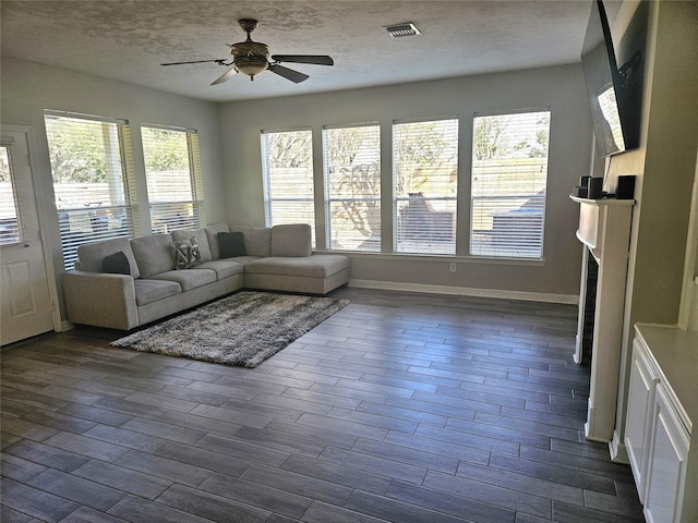 unfurnished living room with ceiling fan, dark wood-type flooring, and a textured ceiling