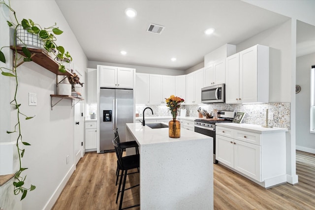 kitchen featuring appliances with stainless steel finishes, light hardwood / wood-style floors, white cabinetry, and sink