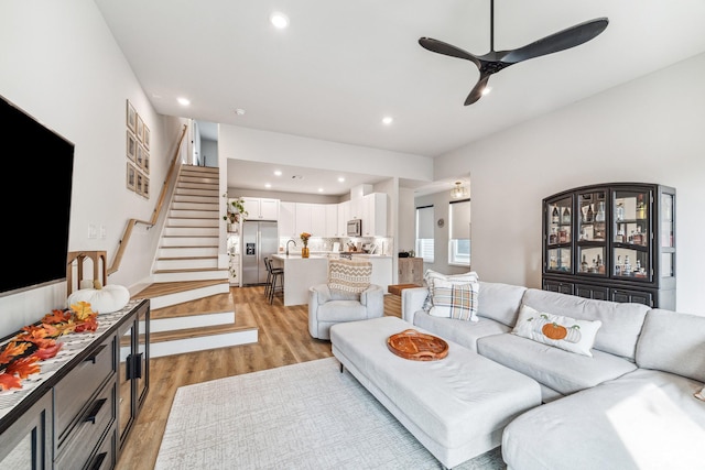 living room with ceiling fan, light wood-type flooring, and sink