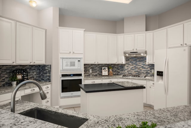 kitchen with white cabinetry, white appliances, sink, and dark stone counters