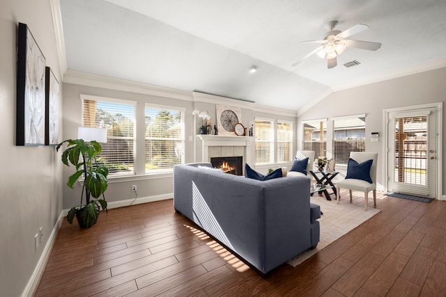 living room featuring ornamental molding, dark wood-type flooring, lofted ceiling, and a tiled fireplace