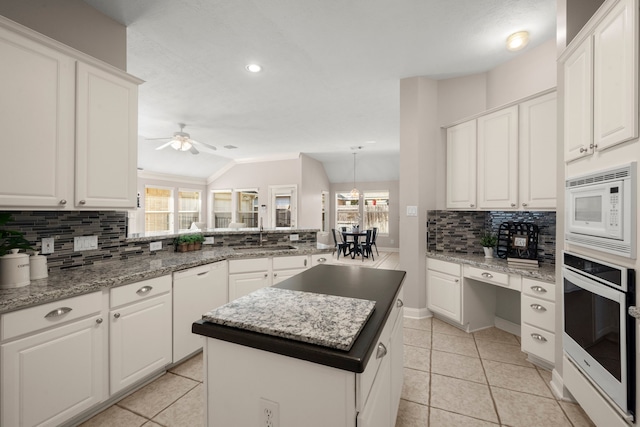 kitchen featuring white cabinets, a kitchen island, white appliances, and lofted ceiling