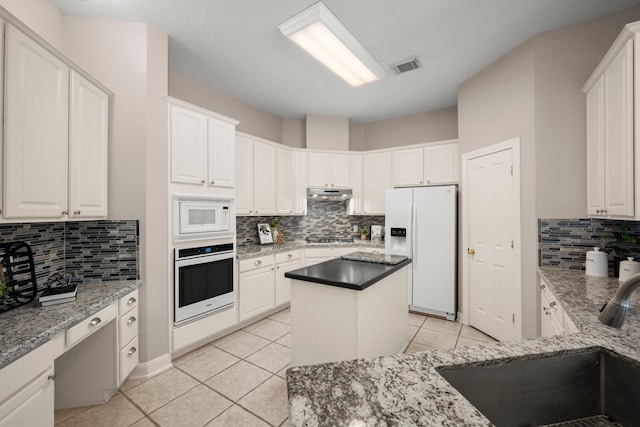 kitchen featuring white cabinets, a kitchen island, light tile patterned flooring, and white appliances